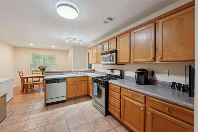 kitchen with stainless steel appliances, a peninsula, light tile patterned floors, a sink, and light countertops