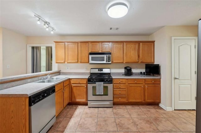 kitchen featuring appliances with stainless steel finishes, a sink, light countertops, light tile patterned flooring, and a peninsula