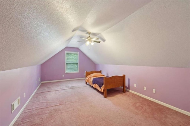 unfurnished bedroom featuring carpet floors, lofted ceiling, a textured ceiling, baseboards, and ceiling fan