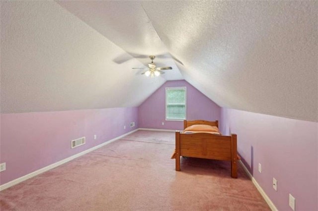 unfurnished bedroom featuring a textured ceiling, carpet flooring, lofted ceiling, ceiling fan, and baseboards