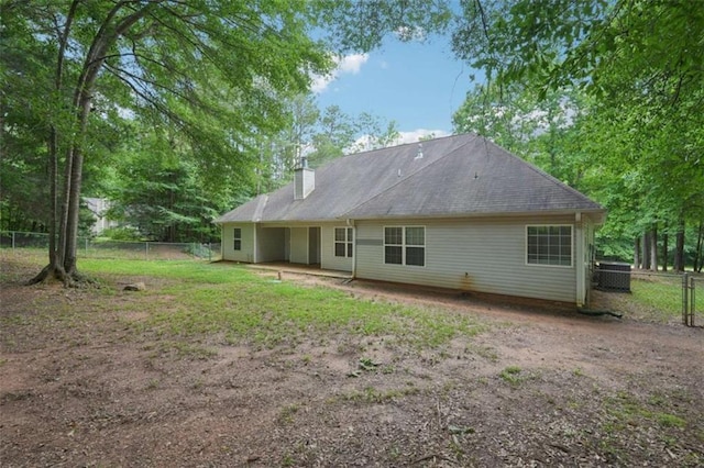 back of property with a fenced backyard, a chimney, central AC unit, and a patio