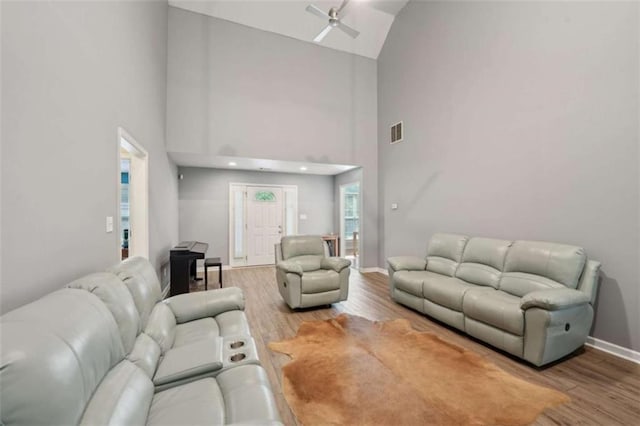 living room with a ceiling fan, wood finished floors, high vaulted ceiling, and baseboards