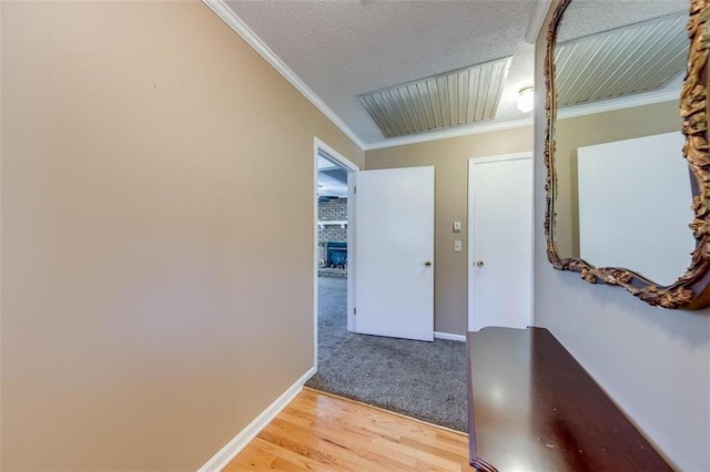 corridor featuring wood-type flooring, a textured ceiling, and ornamental molding