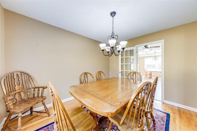 dining room with ceiling fan with notable chandelier and light hardwood / wood-style floors