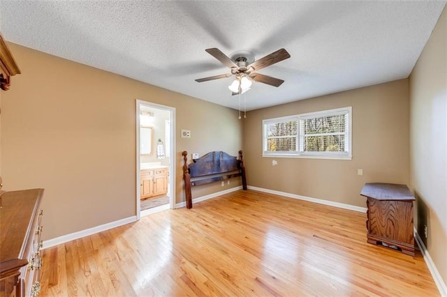 bedroom with a textured ceiling, light wood-type flooring, ceiling fan, and connected bathroom