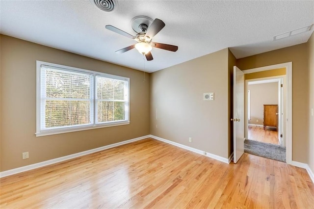 spare room with ceiling fan, light wood-type flooring, and a textured ceiling