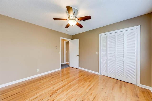 unfurnished bedroom with ceiling fan, a closet, and light wood-type flooring