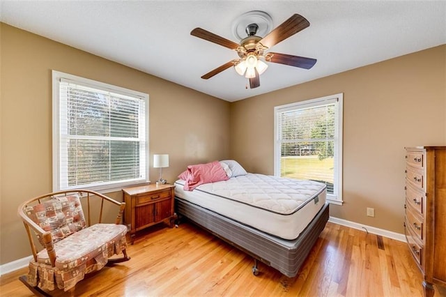 bedroom with light hardwood / wood-style flooring, ceiling fan, and multiple windows