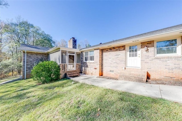 rear view of house with a lawn and a sunroom