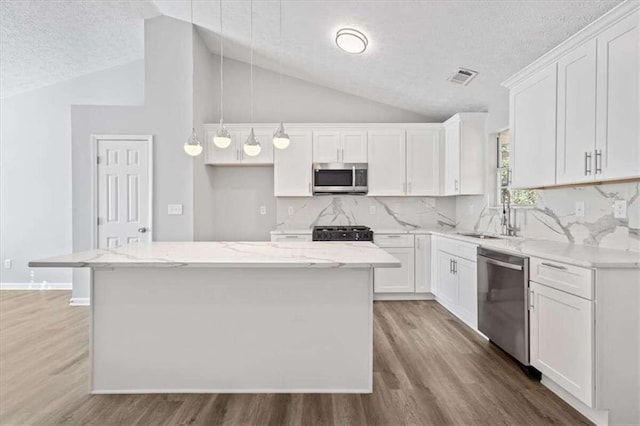 kitchen featuring a kitchen island, hanging light fixtures, a textured ceiling, and appliances with stainless steel finishes