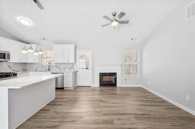 kitchen featuring white cabinetry, stainless steel appliances, decorative light fixtures, and light hardwood / wood-style floors