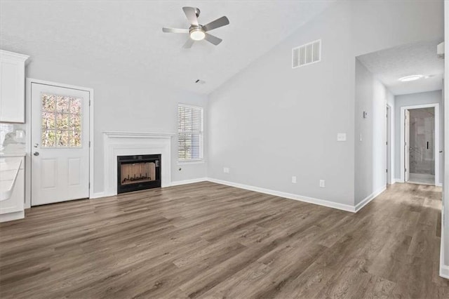 unfurnished living room with a textured ceiling, dark wood-type flooring, ceiling fan, and lofted ceiling