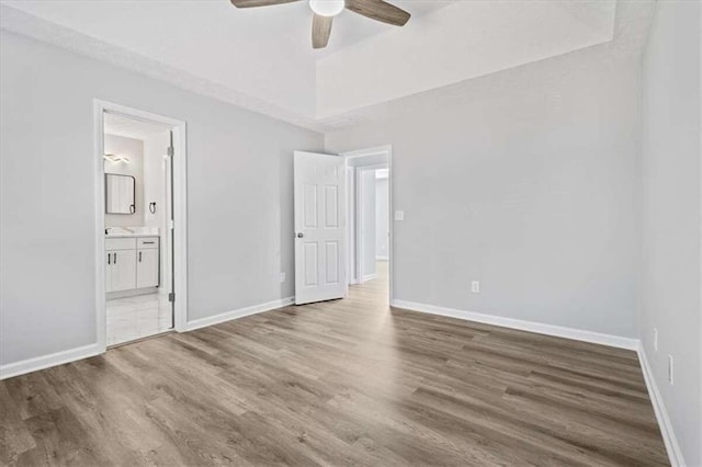 unfurnished bedroom featuring ensuite bathroom, ceiling fan, and hardwood / wood-style flooring