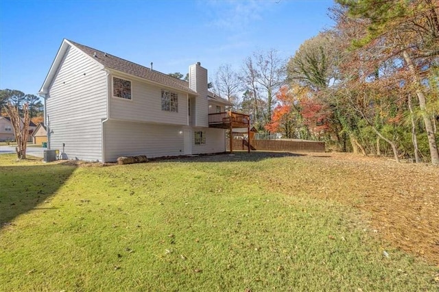 rear view of property featuring a lawn, cooling unit, and a deck