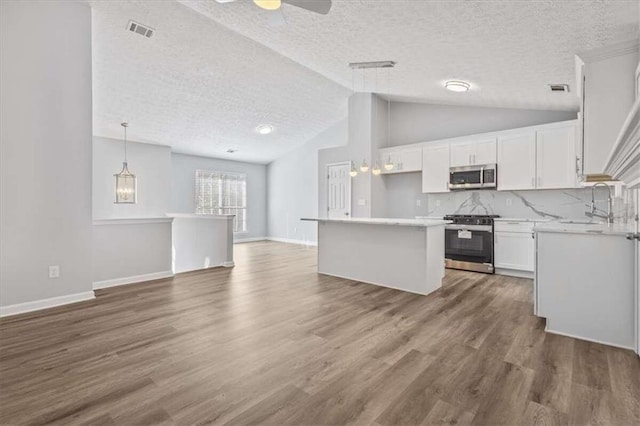 kitchen featuring white cabinets, appliances with stainless steel finishes, dark hardwood / wood-style flooring, and a textured ceiling