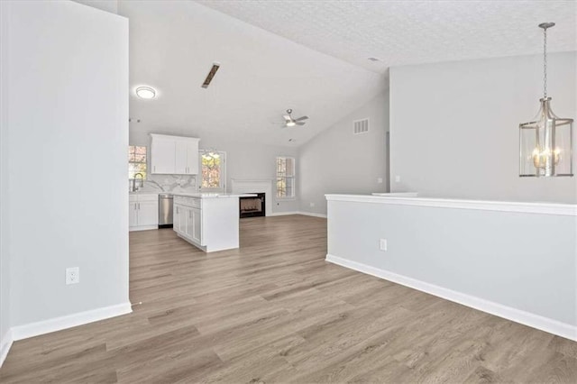 unfurnished living room featuring a textured ceiling, light wood-type flooring, high vaulted ceiling, and ceiling fan