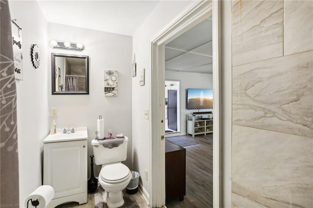 bathroom with toilet, wood finished floors, vanity, and baseboards