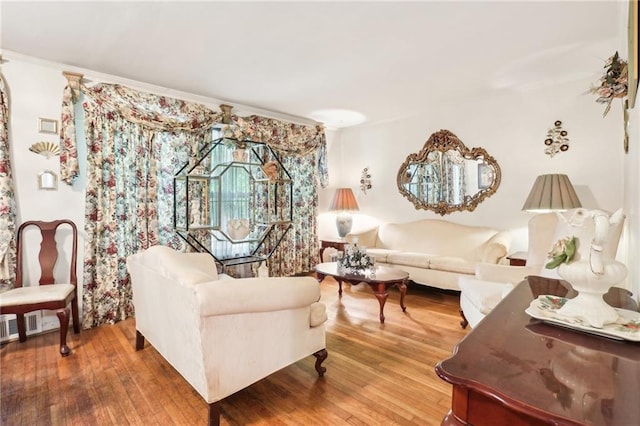 living area with crown molding, hardwood / wood-style floors, and ornate columns