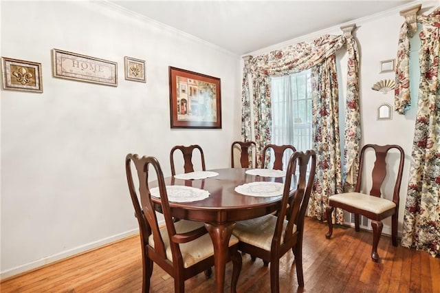 dining room featuring hardwood / wood-style flooring, baseboards, and ornamental molding