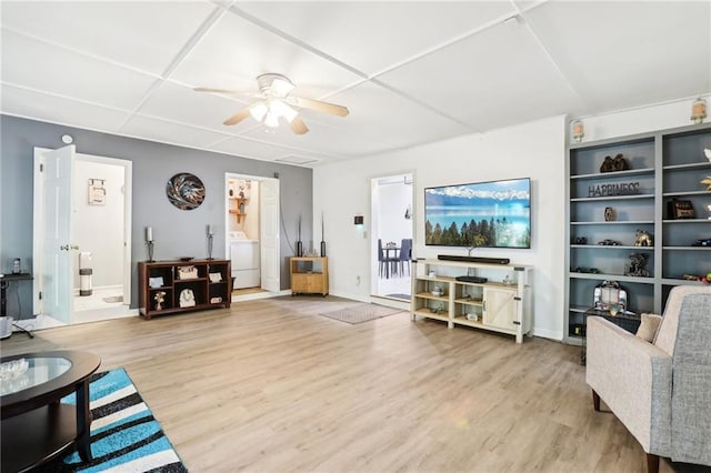 living room with washer / dryer, ceiling fan, baseboards, and wood finished floors