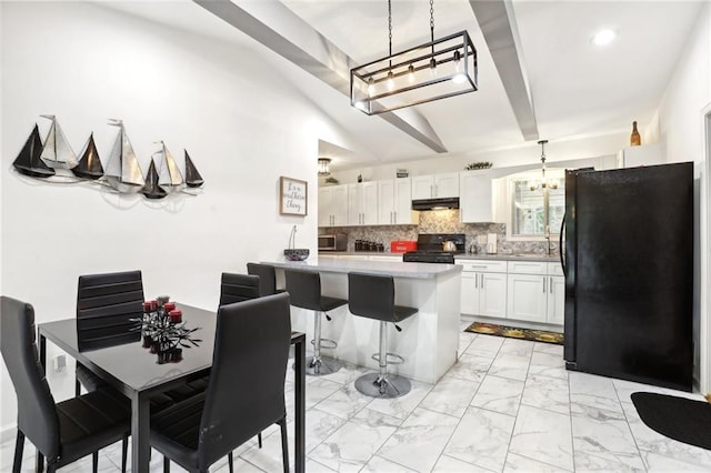 kitchen with marble finish floor, backsplash, freestanding refrigerator, range, and under cabinet range hood