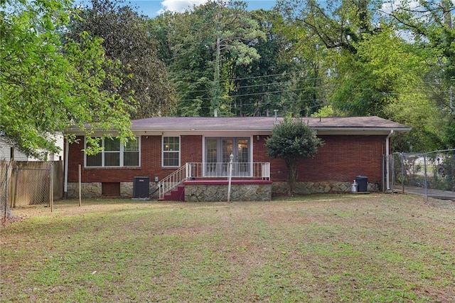 view of front of home with a front lawn, fence, brick siding, and central air condition unit