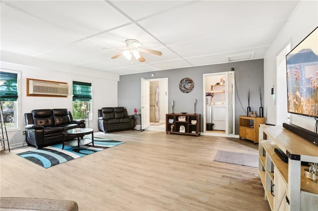 living room featuring attic access, a wall unit AC, ceiling fan, wood finished floors, and independent washer and dryer