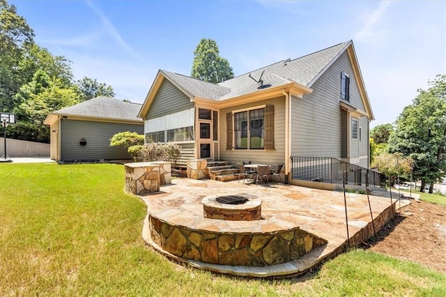 back of property with a sunroom, an outdoor fire pit, a lawn, a shingled roof, and a patio area
