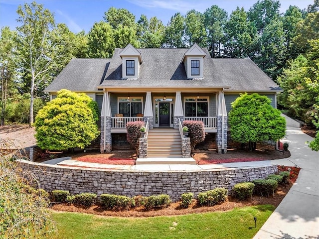 view of front of property featuring stairs, covered porch, and roof with shingles