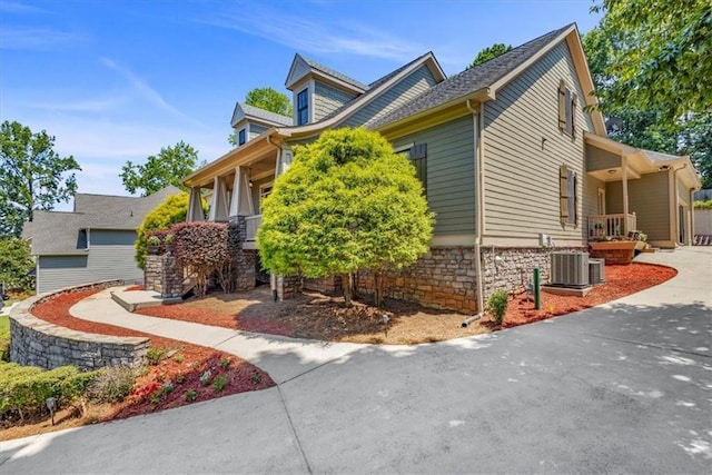view of property exterior featuring central AC unit, driveway, and stone siding