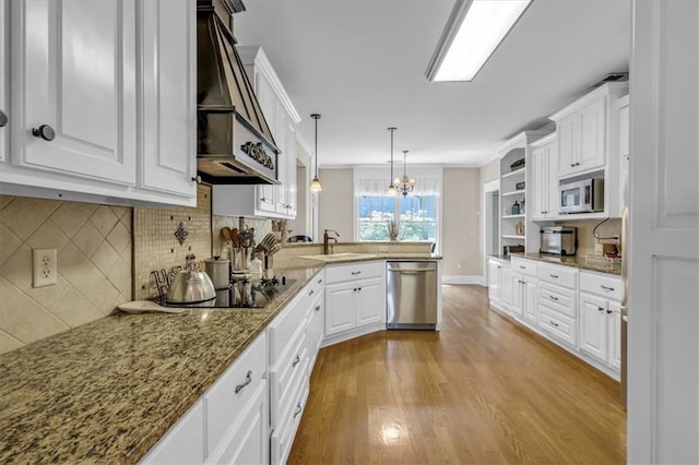 kitchen featuring premium range hood, white cabinets, a peninsula, appliances with stainless steel finishes, and wood finished floors