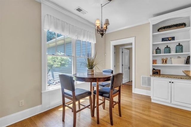 dining room with visible vents, crown molding, light wood-style floors, and an inviting chandelier