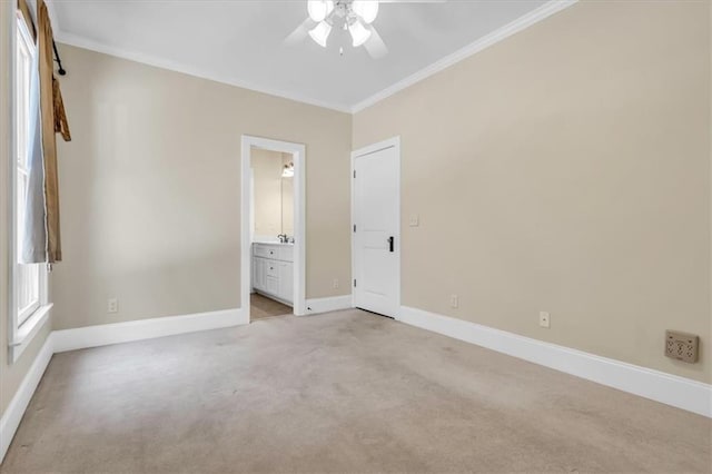 spare room featuring light colored carpet, baseboards, ornamental molding, and a ceiling fan