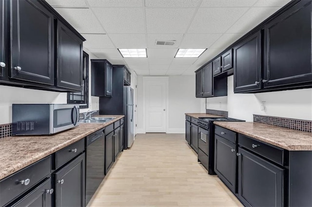kitchen with light countertops, light wood-type flooring, a drop ceiling, visible vents, and black appliances