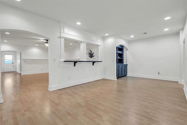 unfurnished living room with light wood-type flooring, arched walkways, ceiling fan, and recessed lighting