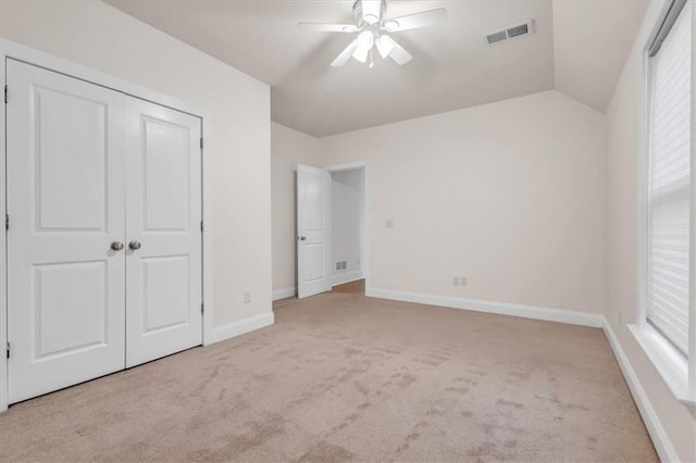 unfurnished bedroom with a closet, carpet floors, lofted ceiling, baseboards, and visible vents