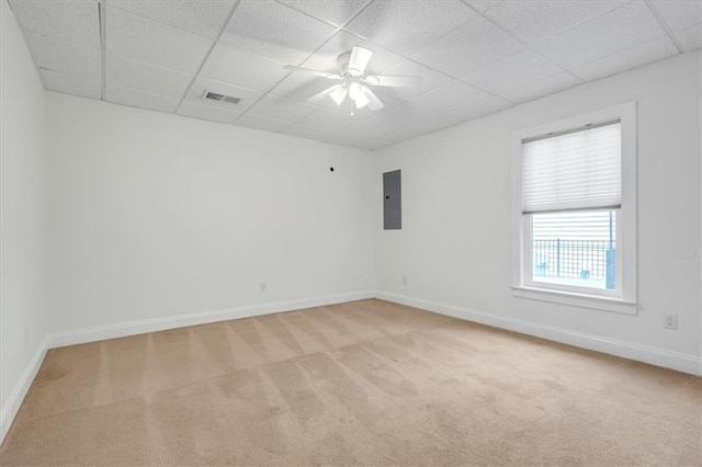 unfurnished room with electric panel, light carpet, baseboards, ceiling fan, and a drop ceiling