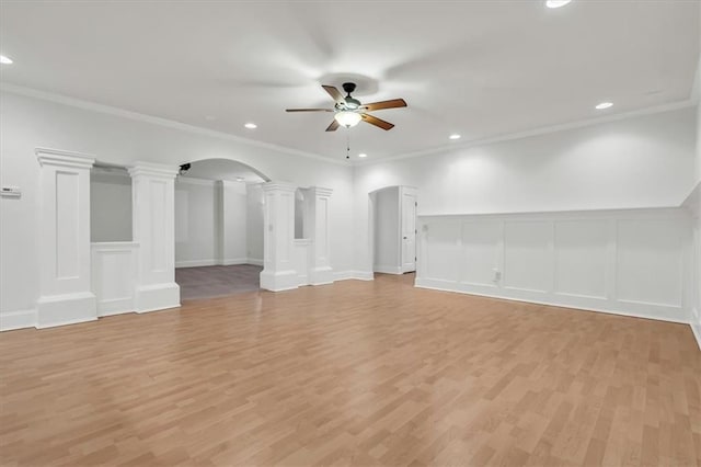 unfurnished living room featuring light wood-type flooring, arched walkways, ceiling fan, and ornate columns