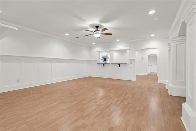 unfurnished living room with light wood-style flooring, crown molding, arched walkways, and ceiling fan
