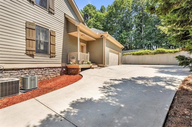view of property exterior with an attached garage, cooling unit, and concrete driveway