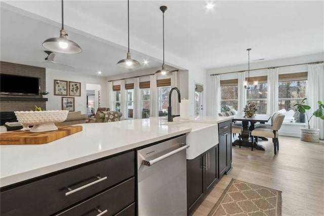 kitchen with hanging light fixtures, light hardwood / wood-style flooring, sink, and dishwasher