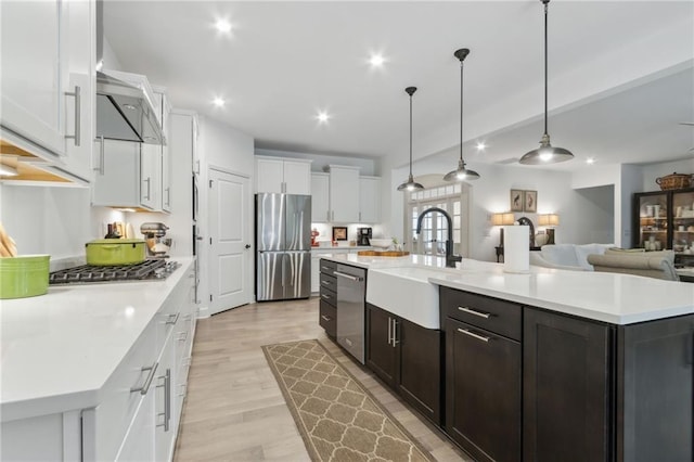 kitchen with appliances with stainless steel finishes, pendant lighting, white cabinetry, sink, and a large island