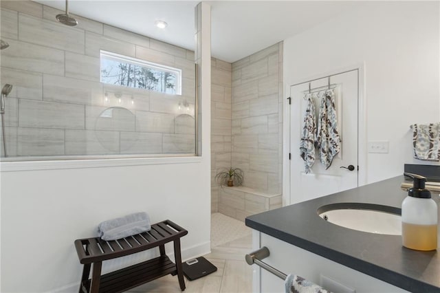 bathroom with a tile shower, vanity, and tile patterned flooring