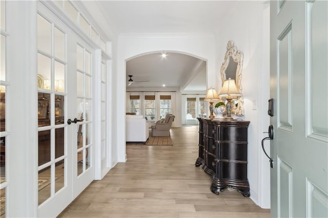 corridor with french doors, ornamental molding, and light hardwood / wood-style floors