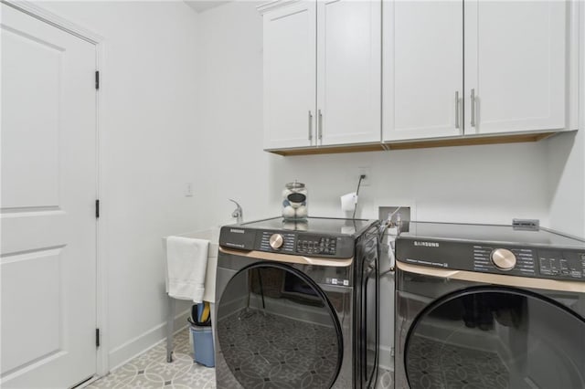 clothes washing area featuring washing machine and dryer and cabinets