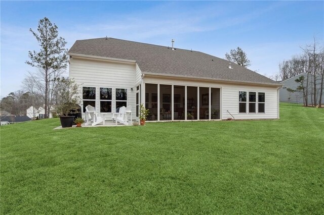 rear view of property featuring a yard, a sunroom, and a patio area