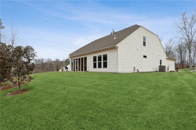 rear view of property with a yard and central air condition unit