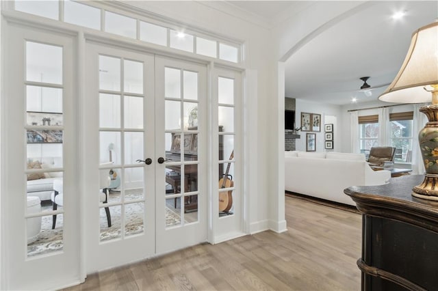 doorway with french doors, crown molding, and light wood-type flooring