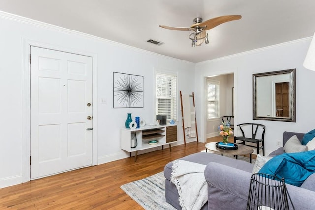 interior space with ornamental molding, wood finished floors, visible vents, and baseboards