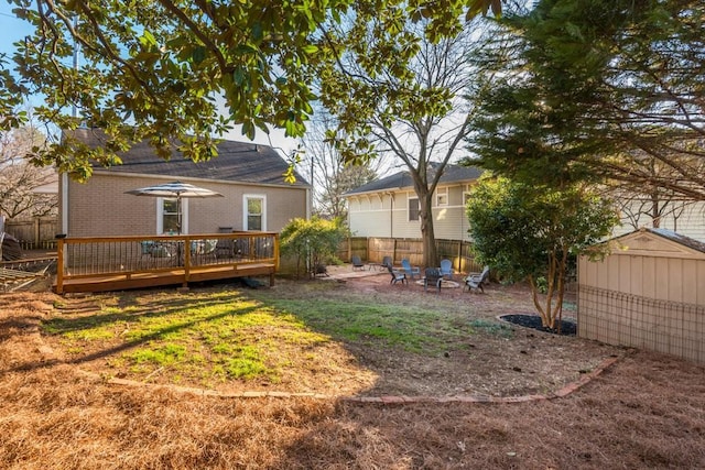 back of property with a fire pit, an outbuilding, fence, a deck, and a shed